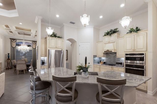 5804 Mulligan Way, Lakewood Ranch, FL 34211 - kitchen with cream cabinets, stainless steel appliances, a chandelier, decorative backsplash, and crown molding