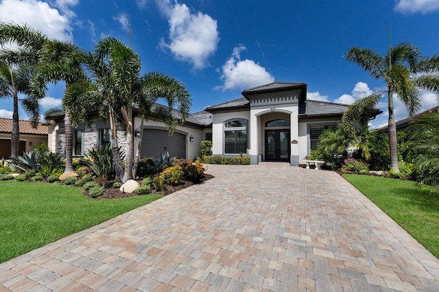 5804 Mulligan Way, Lakewood Ranch, FL 34211 - mediterranean / spanish-style house with french doors, an attached garage, decorative driveway, stucco siding, and a front yard