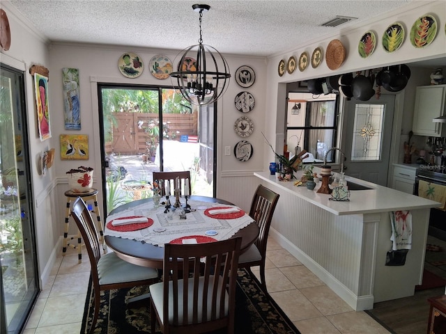 2411 Quail Ct, Bradenton, FL 34209 - dining area featuring a chandelier, light tile patterned floors, a wainscoted wall, a textured ceiling, and ornamental molding