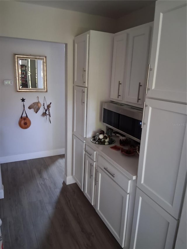 2411 Quail Ct, Bradenton, FL 34209 - kitchen with stainless steel microwave, white cabinetry, light countertops, and dark wood-style floors
