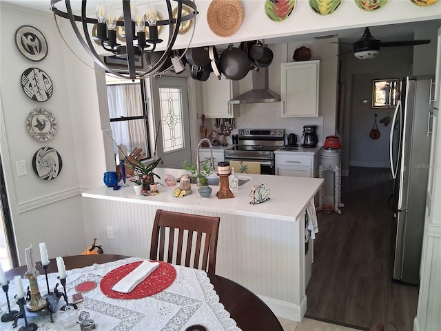 2411 Quail Ct, Bradenton, FL 34209 - kitchen featuring stainless steel appliances, wall chimney range hood, white cabinets, a chandelier, and light countertops