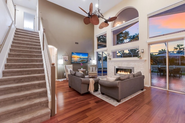 4410 67th Avenue Cir E, Sarasota, FL 34243 - living room featuring wood finished floors, arched walkways, a lit fireplace, a high ceiling, and stairway