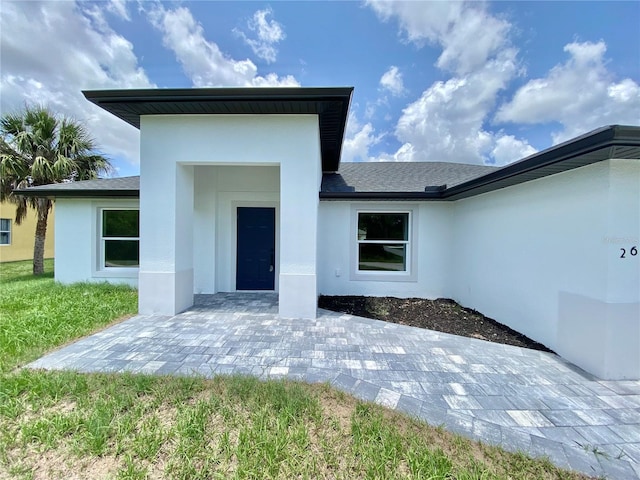 2692 Pretzel Ln, North Port, FL 34286 - view of exterior entry featuring stucco siding, a patio area, and roof with shingles