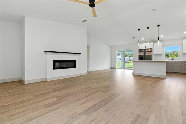 2692 Pretzel Ln, North Port, FL 34286 - unfurnished living room with light wood-style flooring, a glass covered fireplace, recessed lighting, a ceiling fan, and lofted ceiling