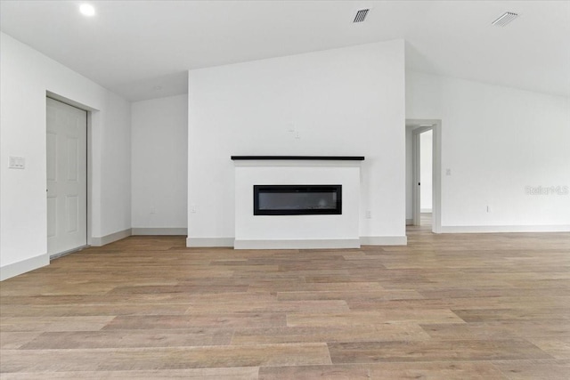 2692 Pretzel Ln, North Port, FL 34286 - unfurnished living room featuring a glass covered fireplace and light wood-style flooring