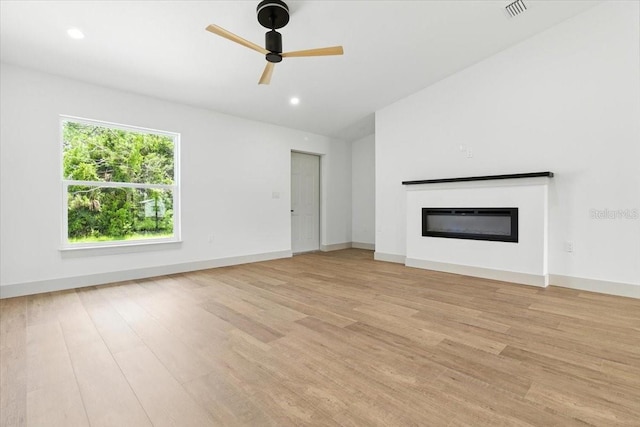 2692 Pretzel Ln, North Port, FL 34286 - unfurnished living room featuring a glass covered fireplace, light wood-type flooring, a ceiling fan, and recessed lighting
