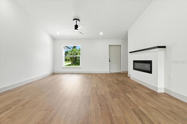 2692 Pretzel Ln, North Port, FL 34286 - unfurnished living room with a glass covered fireplace, a ceiling fan, light wood-type flooring, and recessed lighting