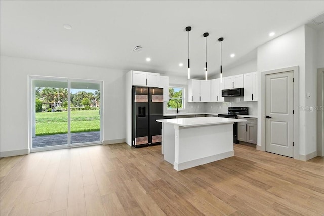 2692 Pretzel Ln, North Port, FL 34286 - kitchen with refrigerator with ice dispenser, black electric range oven, decorative backsplash, a kitchen island, and light countertops