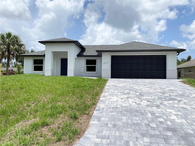 2692 Pretzel Ln, North Port, FL 34286 - prairie-style home featuring stucco siding, an attached garage, decorative driveway, and a front lawn