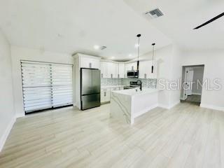 5009 Jody Ave, North Port, FL 34288 - kitchen with freestanding refrigerator, stainless steel microwave, light countertops, a peninsula, and white cabinets
