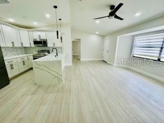 5009 Jody Ave, North Port, FL 34288 - kitchen featuring stainless steel microwave, white cabinets, stove, light countertops, and light wood finished floors