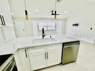 5009 Jody Ave, North Port, FL 34288 - kitchen with dishwasher, light stone counters, white cabinetry, and decorative light fixtures
