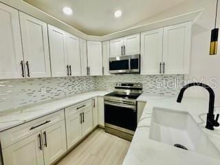 5009 Jody Ave, North Port, FL 34288 - kitchen with stainless steel appliances, recessed lighting, tasteful backsplash, white cabinetry, and light wood-type flooring