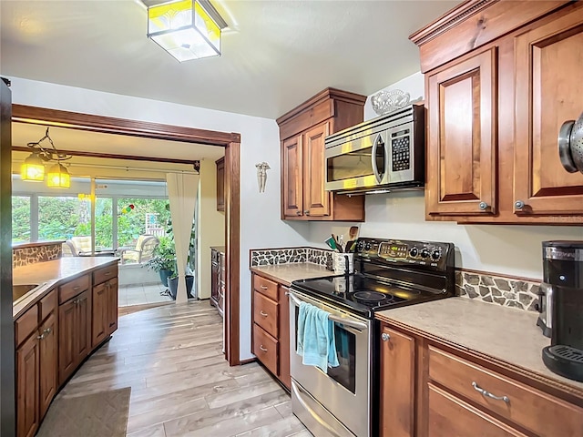408 67th Ave W, Bradenton, FL 34207 - kitchen with appliances with stainless steel finishes, light wood-type flooring, and brown cabinetry