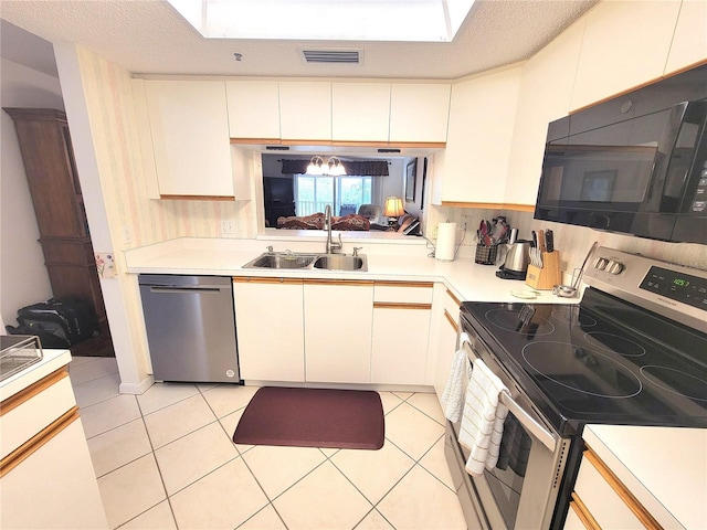 6507 Stone River Rd Unit 302, Bradenton, FL 34203 - kitchen with stainless steel appliances, light countertops, light tile patterned floors, a skylight, and white cabinetry