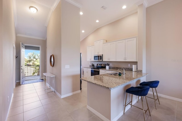 13714 Messina Loop Unit 202, Bradenton, FL 34211 - kitchen featuring appliances with stainless steel finishes, crown molding, light stone counters, white cabinets, and a kitchen bar