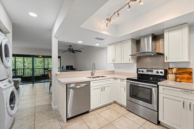 3003 Quail Holw Unit 10, Sarasota, FL 34235 - kitchen with appliances with stainless steel finishes, wall chimney range hood, stacked washer / dryer, light tile patterned floors, and light countertops