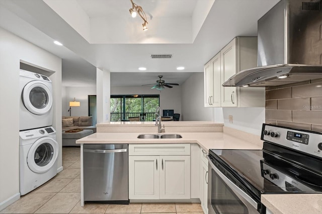 3003 Quail Holw Unit 10, Sarasota, FL 34235 - kitchen featuring appliances with stainless steel finishes, stacked washer / dryer, wall chimney exhaust hood, light countertops, and a peninsula