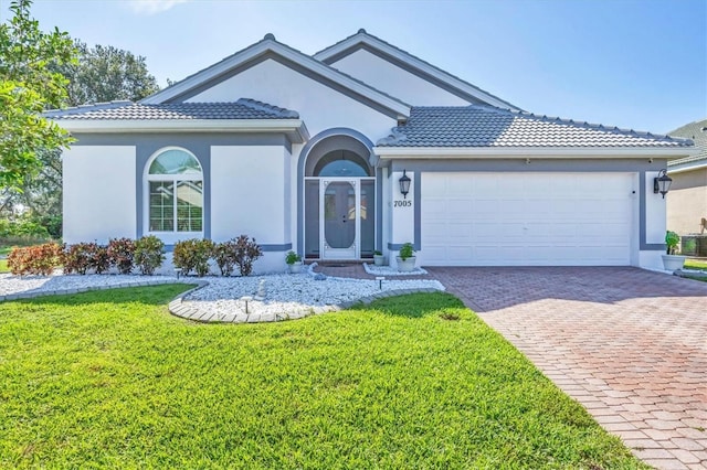 7005 Goldrush Ln, Bradenton, FL 34201 - view of front of house featuring stucco siding, driveway, a front lawn, a garage, and a tile roof