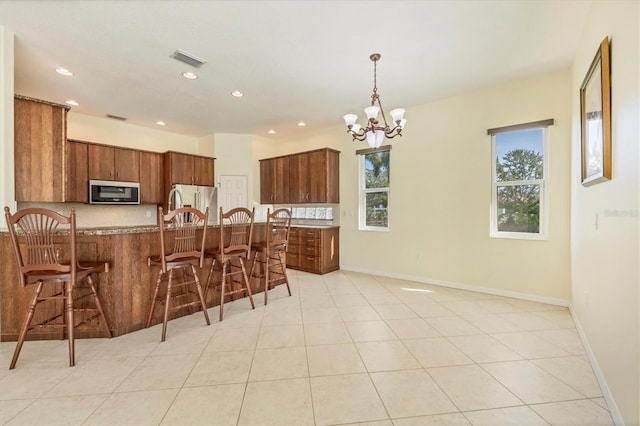 7005 Goldrush Ln, Bradenton, FL 34201 - kitchen with stainless steel appliances, brown cabinetry, plenty of natural light, a peninsula, and recessed lighting