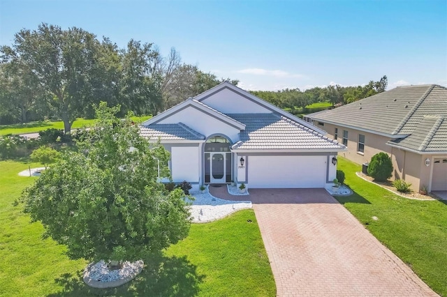 7005 Goldrush Ln, Bradenton, FL 34201 - view of front facade with decorative driveway, an attached garage, a front lawn, stucco siding, and a tiled roof