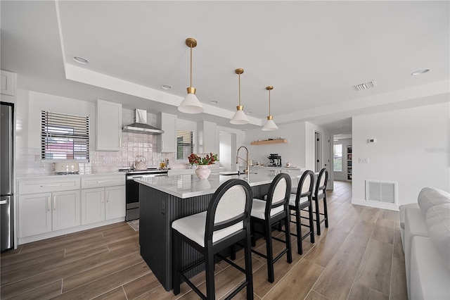 326 Randolph Rd, Venice, FL 34293 - kitchen featuring appliances with stainless steel finishes, wall chimney range hood, a raised ceiling, light countertops, and white cabinetry