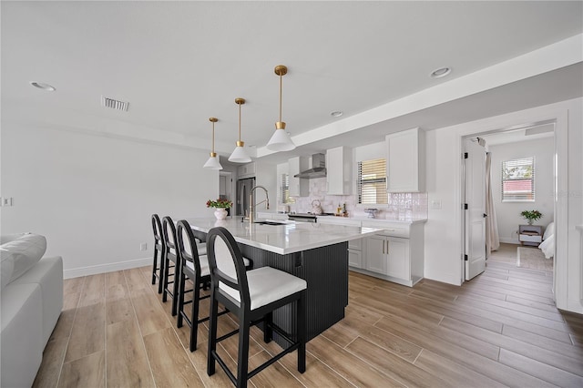 326 Randolph Rd, Venice, FL 34293 - kitchen featuring wall chimney exhaust hood, light wood-style floors, a kitchen breakfast bar, white cabinets, and light countertops