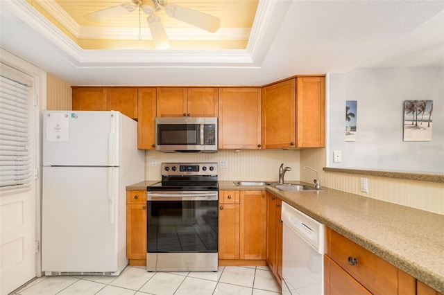 2110 Benjamin Franklin Dr Unit 301, Sarasota, FL 34236 - kitchen with stainless steel appliances, a tray ceiling, brown cabinets, a ceiling fan, and crown molding
