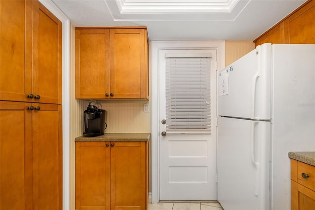 2110 Benjamin Franklin Dr Unit 301, Sarasota, FL 34236 - kitchen featuring freestanding refrigerator, brown cabinets, and light tile patterned floors