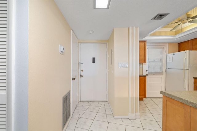 2110 Benjamin Franklin Dr Unit 301, Sarasota, FL 34236 - kitchen with freestanding refrigerator, light tile patterned flooring, a ceiling fan, brown cabinetry, and a raised ceiling