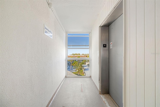 2110 Benjamin Franklin Dr Unit 301, Sarasota, FL 34236 - corridor featuring light colored carpet, elevator, a textured ceiling, floor to ceiling windows, and a textured wall