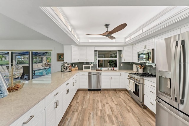 6105 45th St W, Bradenton, FL 34210 - kitchen featuring appliances with stainless steel finishes, a tray ceiling, ceiling fan, light wood-style floors, and white cabinets