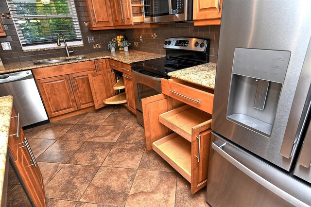 3985 Maceachen Blvd Unit 224, Sarasota, FL 34233 - kitchen with stainless steel appliances, backsplash, brown cabinetry, and light stone counters