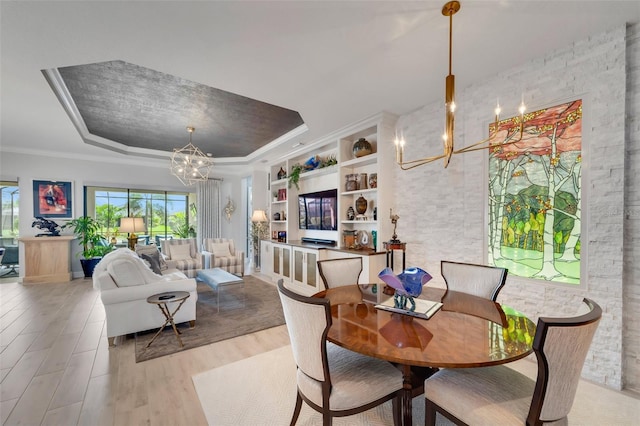 5469 Lampiasi St, Sarasota, FL 34238 - dining space with a chandelier, a raised ceiling, light wood-style flooring, built in shelves, and ornamental molding