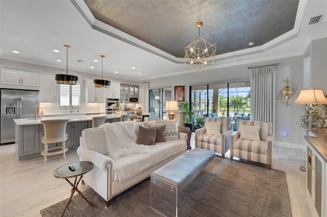 5469 Lampiasi St, Sarasota, FL 34238 - living room with a tray ceiling, ornamental molding, light wood-type flooring, a chandelier, and recessed lighting