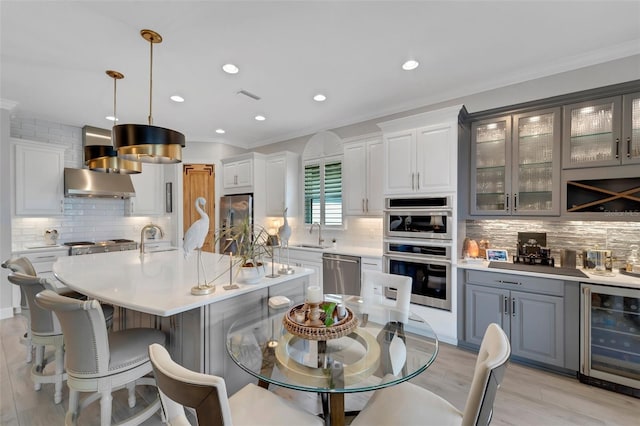 5469 Lampiasi St, Sarasota, FL 34238 - dining space with wine cooler, ornamental molding, recessed lighting, light wood finished floors, and bar with sink