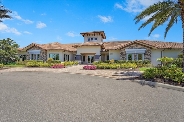 5469 Lampiasi St, Sarasota, FL 34238 - mediterranean / spanish house with stone siding, a tiled roof, stucco siding, and french doors