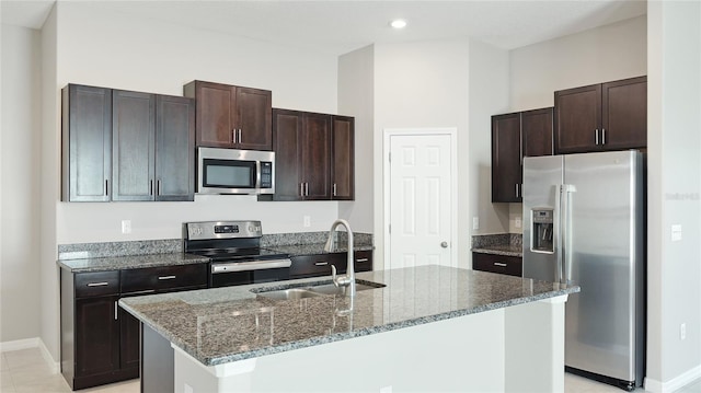 5327 Olano St, Palmetto, FL 34221 - kitchen featuring stainless steel appliances, dark brown cabinets, dark stone counters, a center island with sink, and recessed lighting