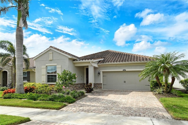 11625 Renaissance Blvd, Venice, FL 34293 - view of front of home with stucco siding, a garage, decorative driveway, stone siding, and a tiled roof