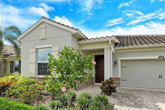 11625 Renaissance Blvd, Venice, FL 34293 - view of front of home featuring a tile roof, an attached garage, stone siding, stucco siding, and driveway