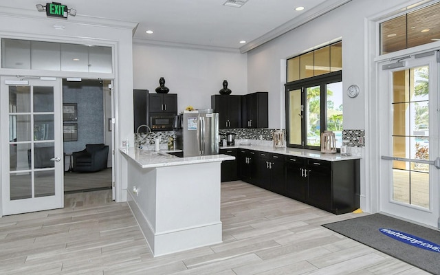 11625 Renaissance Blvd, Venice, FL 34293 - kitchen featuring freestanding refrigerator, dark cabinetry, black microwave, tasteful backsplash, and a peninsula