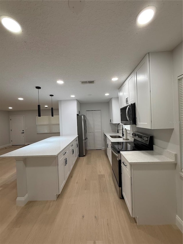 4661 Linwood St, Sarasota, FL 34232 - kitchen featuring appliances with stainless steel finishes, white cabinets, light wood-style floors, recessed lighting, and a textured ceiling