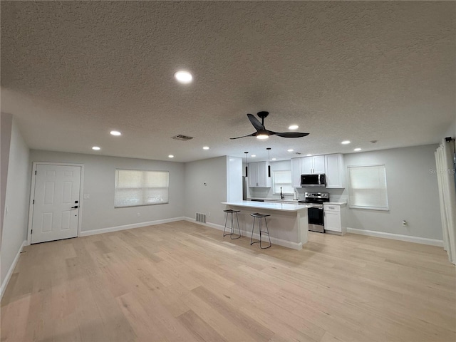 4661 Linwood St, Sarasota, FL 34232 - kitchen featuring stainless steel appliances, a textured ceiling, light wood-style floors, light countertops, and white cabinets