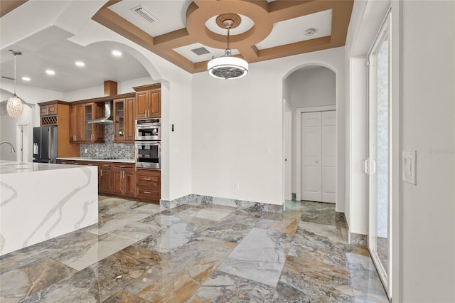 5714 38th Ave E, Bradenton, FL 34208 - kitchen featuring coffered ceiling, arched walkways, brown cabinetry, appliances with stainless steel finishes, and wall chimney exhaust hood