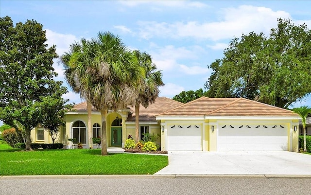 4724 White Tail Ln, Sarasota, FL 34238 - view of front of house featuring an attached garage, driveway, a front lawn, stucco siding, and a tile roof