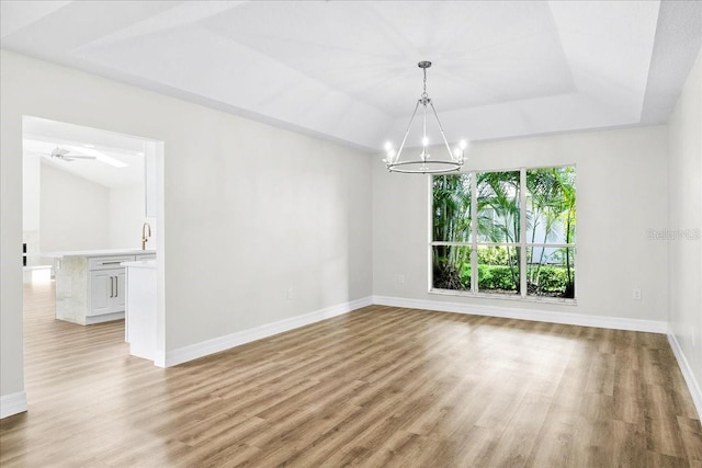 4724 White Tail Ln, Sarasota, FL 34238 - spare room with a chandelier, light wood-style flooring, a tray ceiling, and ceiling fan