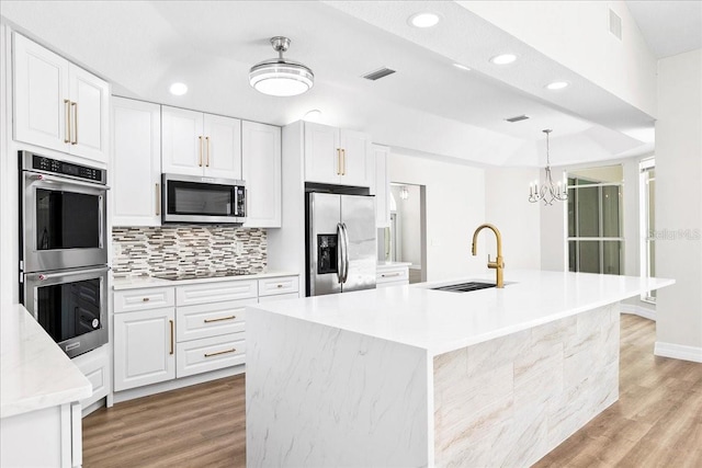 4724 White Tail Ln, Sarasota, FL 34238 - kitchen with stainless steel appliances, recessed lighting, white cabinets, light wood finished floors, and tasteful backsplash