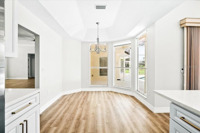 4724 White Tail Ln, Sarasota, FL 34238 - unfurnished dining area with a chandelier, a tray ceiling, and light wood-style floors