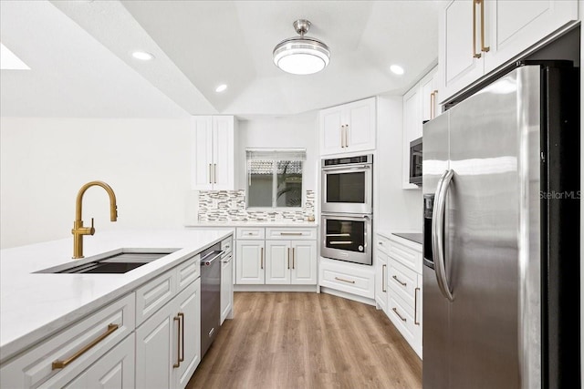4724 White Tail Ln, Sarasota, FL 34238 - kitchen featuring appliances with stainless steel finishes, light countertops, white cabinetry, light wood-style floors, and recessed lighting