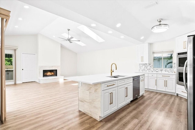 4724 White Tail Ln, Sarasota, FL 34238 - kitchen featuring appliances with stainless steel finishes, a skylight, light wood-style floors, a kitchen island with sink, and vaulted ceiling